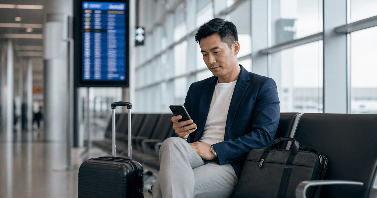 Asian business traveller checking meeting details on a phone at an airport gate